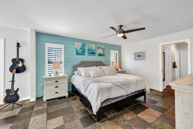 bedroom with wood walls and ceiling fan