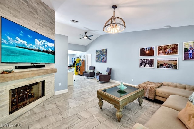 living room with ceiling fan with notable chandelier, vaulted ceiling, and a stone fireplace