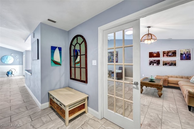 hall featuring vaulted ceiling, a notable chandelier, and french doors