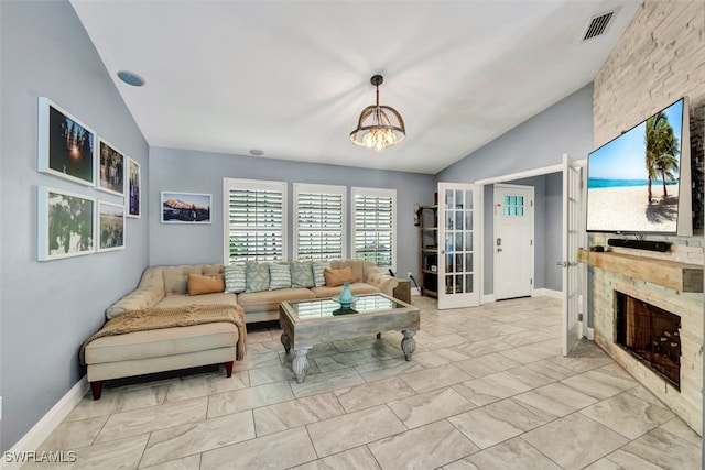 living room featuring lofted ceiling, a notable chandelier, and a stone fireplace