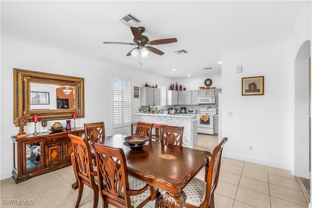 dining room featuring crown molding, light tile patterned floors, and ceiling fan