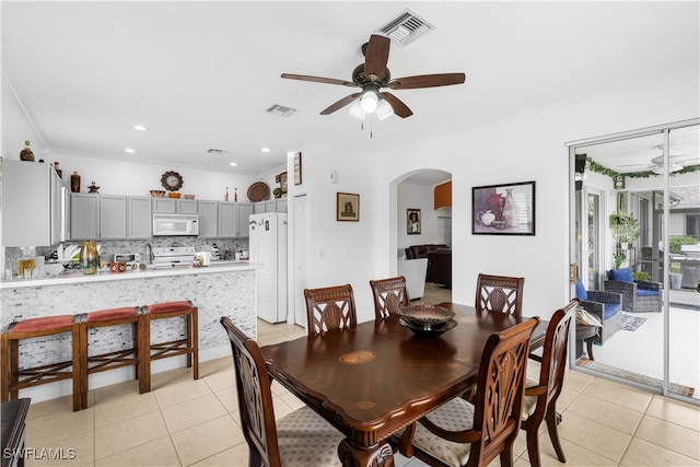 tiled dining area featuring crown molding and ceiling fan