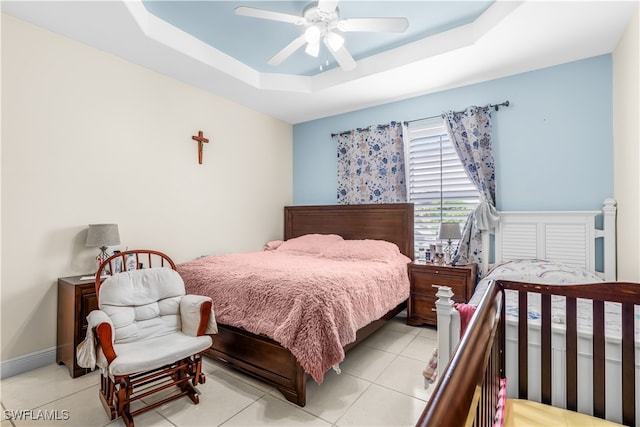 bedroom featuring a raised ceiling, ceiling fan, and light tile patterned floors