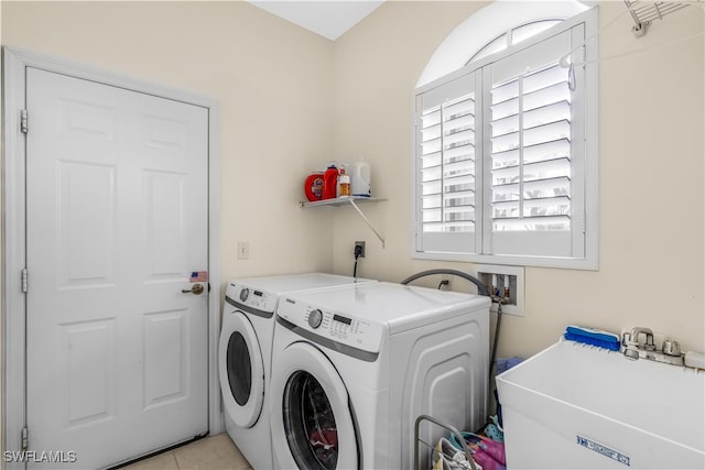 laundry area with light tile patterned floors, washer and clothes dryer, and sink