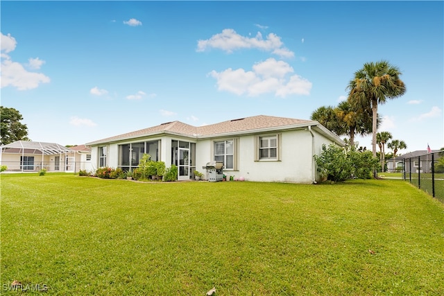 rear view of property with a sunroom and a lawn