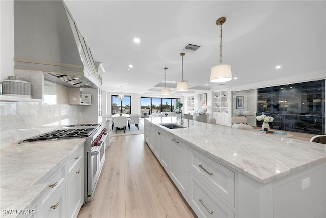 kitchen featuring range with gas stovetop, visible vents, light wood-style flooring, open floor plan, and a sink