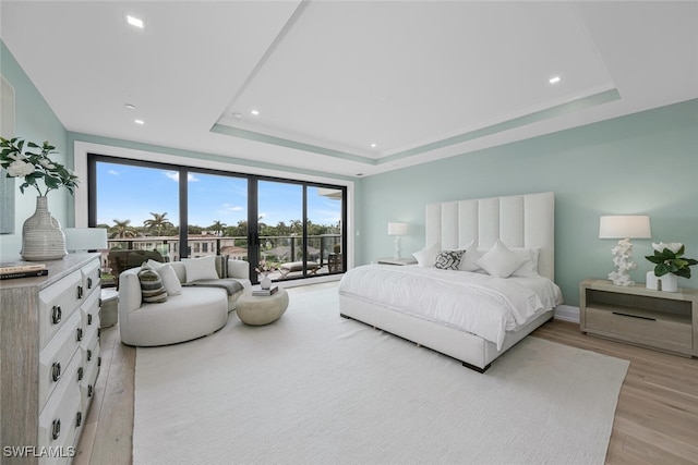 bedroom featuring a tray ceiling, light wood finished floors, recessed lighting, access to outside, and baseboards