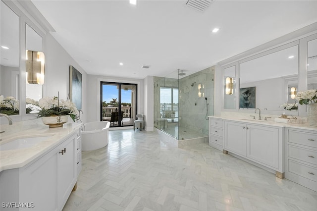 full bath featuring a shower stall, visible vents, two vanities, and a sink