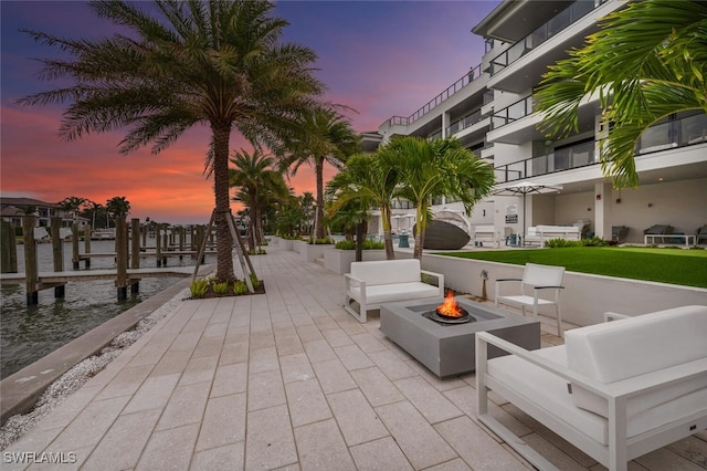 view of home's community featuring a patio, a dock, and an outdoor living space with a fire pit