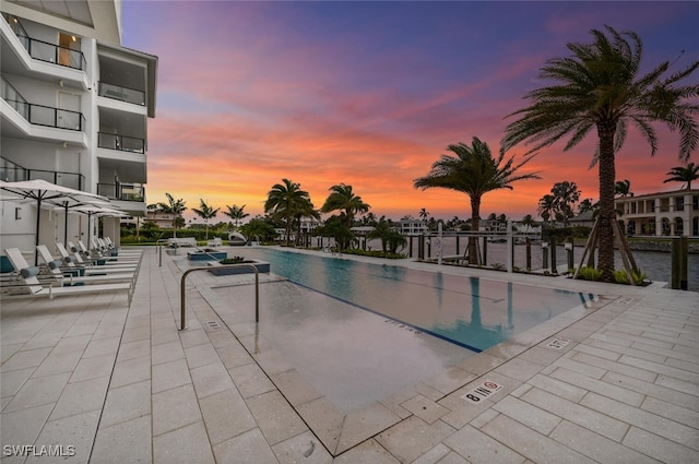 pool at dusk with a patio and a community pool