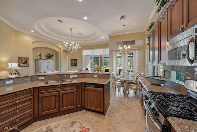 kitchen with light stone countertops, stainless steel appliances, an inviting chandelier, and a sink