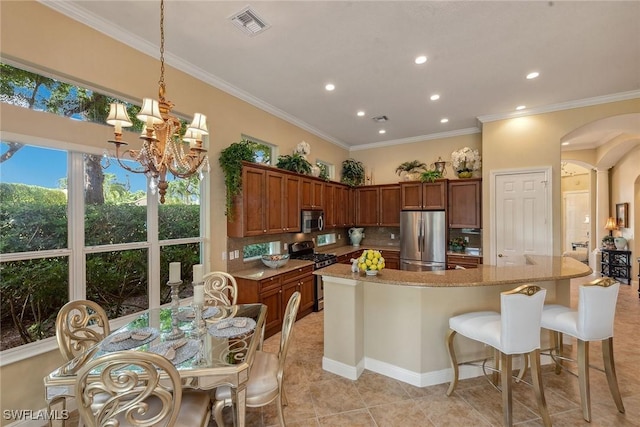 kitchen featuring tasteful backsplash, visible vents, brown cabinetry, appliances with stainless steel finishes, and arched walkways