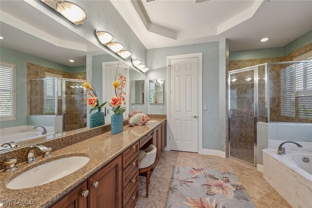 bathroom featuring a tray ceiling, vanity, and separate shower and tub