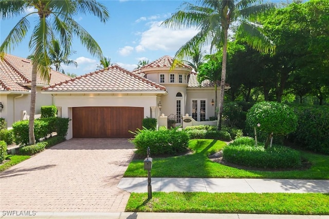 mediterranean / spanish-style home featuring stucco siding, decorative driveway, french doors, an attached garage, and a tiled roof