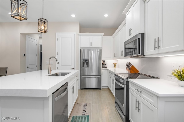 kitchen with appliances with stainless steel finishes, a center island with sink, and white cabinetry