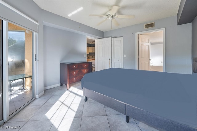 tiled bedroom featuring a textured ceiling, ceiling fan, and connected bathroom