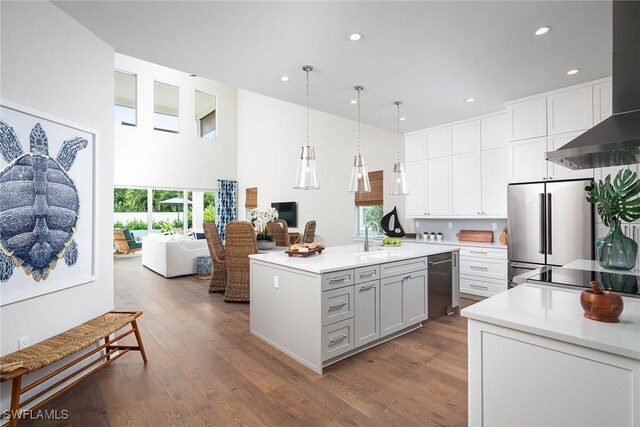 kitchen with appliances with stainless steel finishes, a center island with sink, dark hardwood / wood-style flooring, and pendant lighting