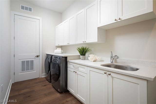 laundry area featuring cabinets, dark hardwood / wood-style floors, sink, and washing machine and clothes dryer