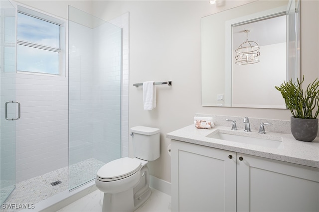 bathroom with an inviting chandelier, vanity, toilet, and a shower with shower door