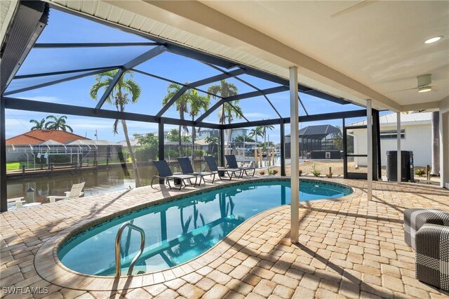 view of pool with glass enclosure, a water view, and a patio