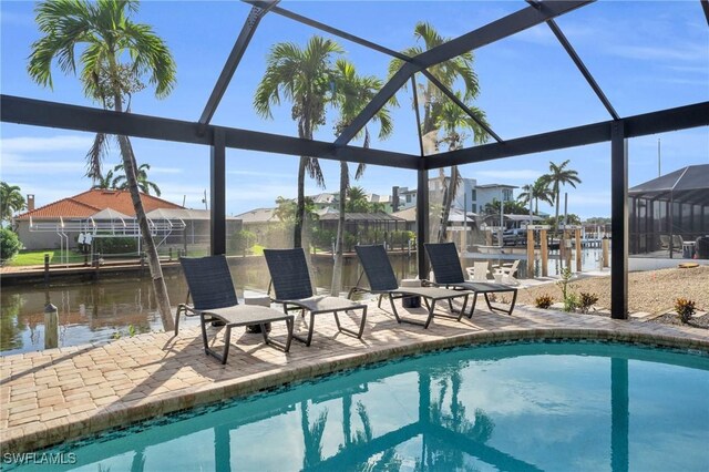 view of swimming pool featuring glass enclosure, a water view, and a patio