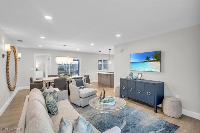 living room featuring an inviting chandelier and light hardwood / wood-style flooring