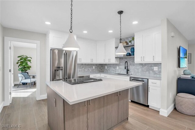 kitchen with white cabinets, sink, light hardwood / wood-style flooring, appliances with stainless steel finishes, and a kitchen island