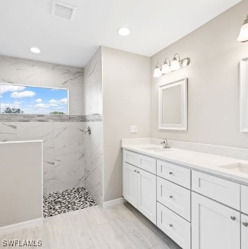 bathroom featuring tiled shower and vanity