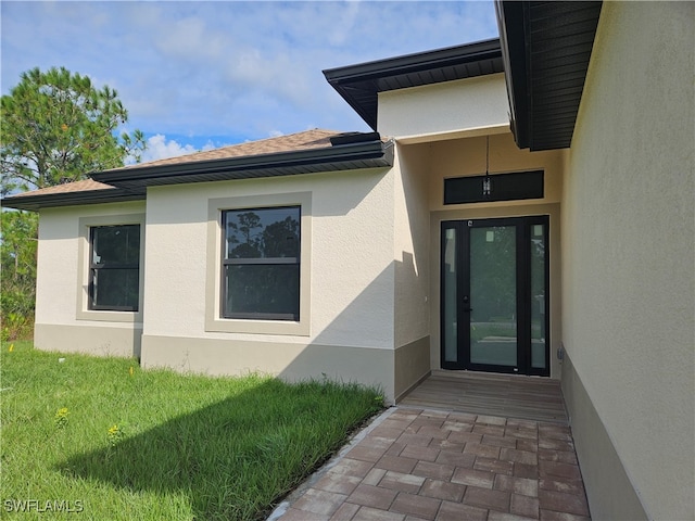 view of exterior entry featuring a lawn