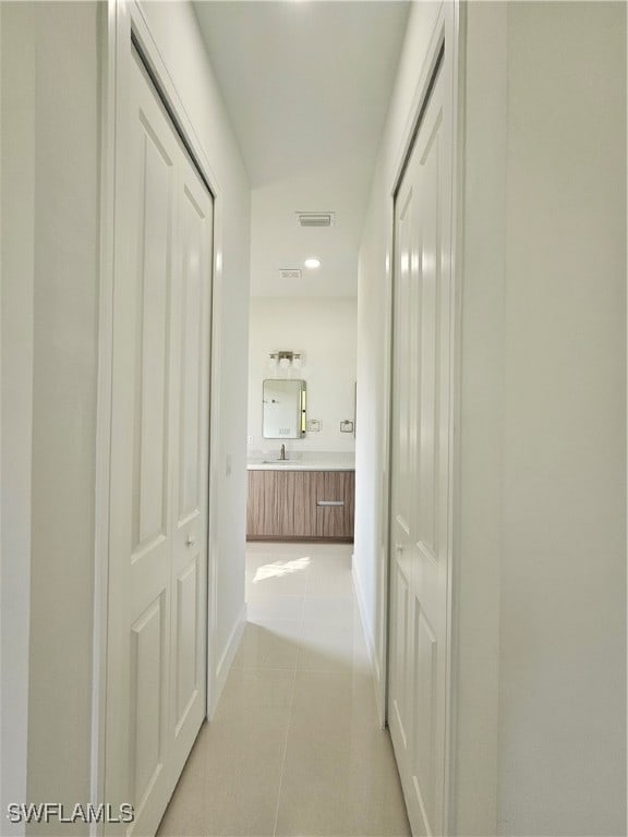 corridor featuring light tile patterned floors and sink