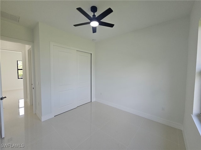 unfurnished bedroom with light tile patterned floors, a closet, and ceiling fan