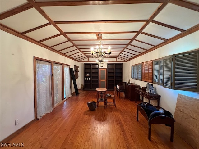 living area featuring hardwood / wood-style floors, vaulted ceiling, and a notable chandelier