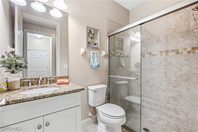 bathroom featuring vanity, toilet, and a shower with shower door