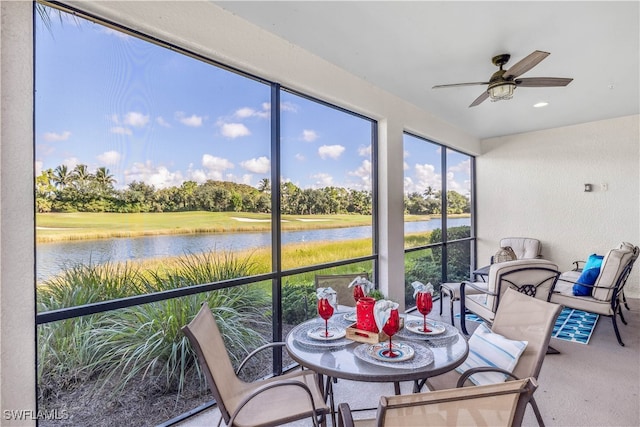 sunroom / solarium featuring a water view and ceiling fan