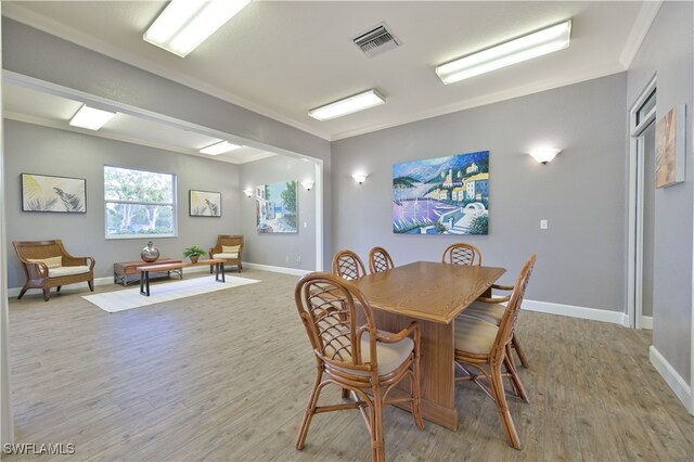 dining area with crown molding and light hardwood / wood-style flooring