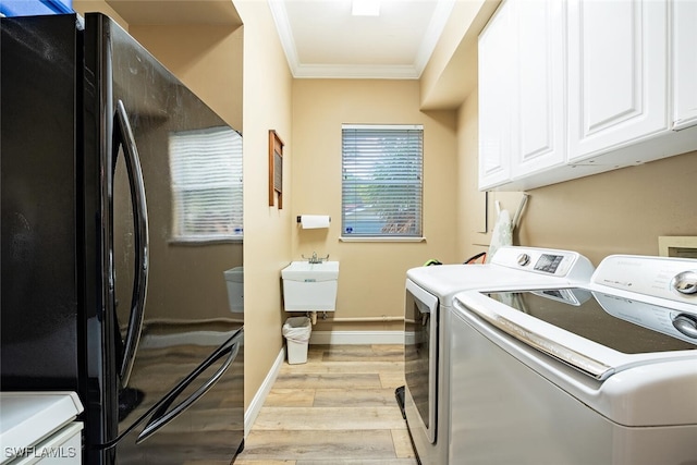 laundry area featuring cabinets, ornamental molding, light hardwood / wood-style flooring, washing machine and clothes dryer, and sink