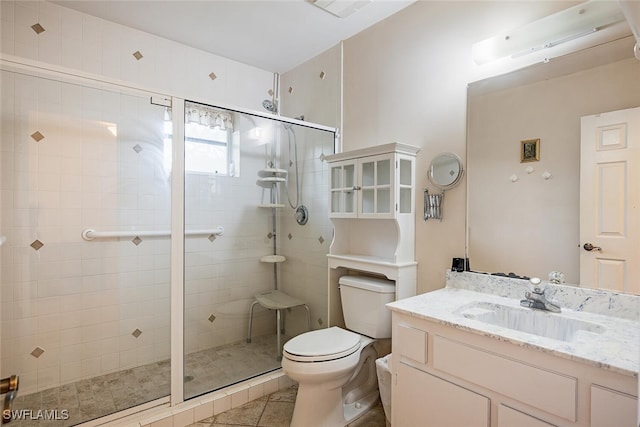 bathroom featuring a shower with door, vanity, toilet, and tile patterned floors