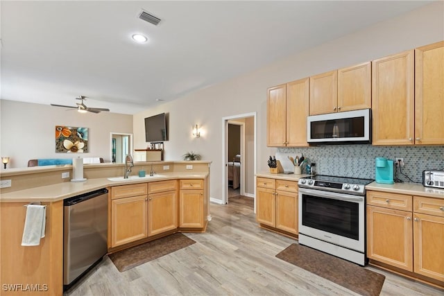 kitchen featuring appliances with stainless steel finishes, tasteful backsplash, light hardwood / wood-style flooring, and sink