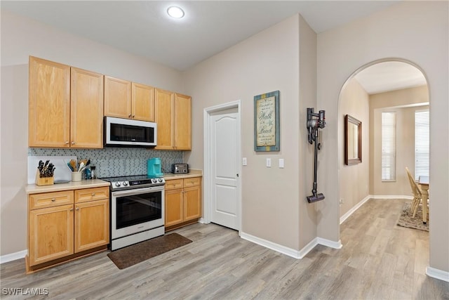 kitchen with electric range, light wood-type flooring, backsplash, and light brown cabinets