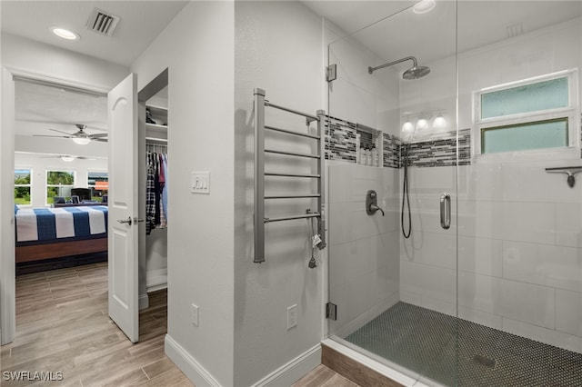 bathroom with hardwood / wood-style floors, a shower with door, radiator, and ceiling fan