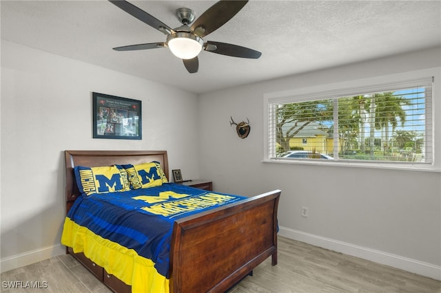 bedroom featuring ceiling fan, baseboards, and wood finished floors
