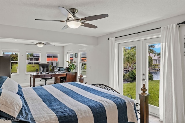 bedroom featuring french doors, wood finished floors, a ceiling fan, a water view, and access to outside