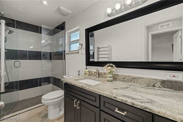bathroom with a stall shower, toilet, visible vents, vanity, and wood finished floors