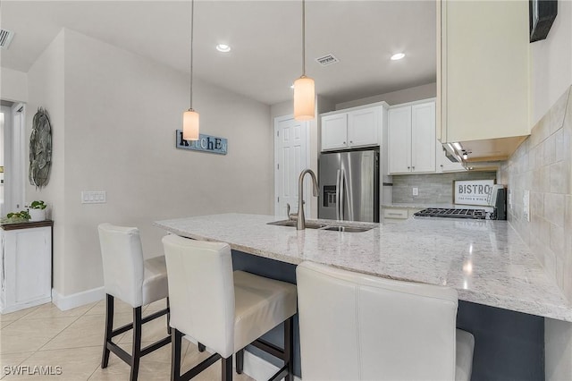 kitchen featuring stove, hanging light fixtures, a kitchen breakfast bar, stainless steel refrigerator with ice dispenser, and white cabinets