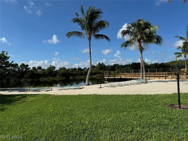 surrounding community with a water view and a lawn