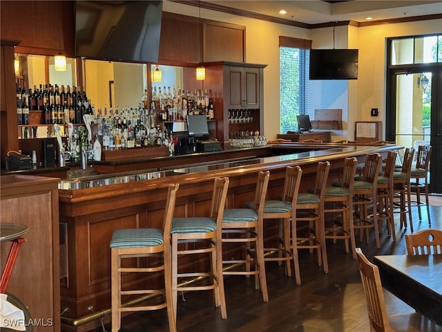 bar featuring ornamental molding and dark hardwood / wood-style flooring