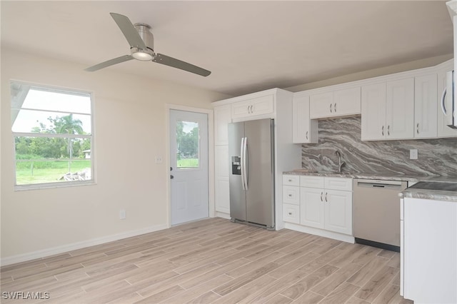 kitchen featuring appliances with stainless steel finishes, decorative backsplash, white cabinetry, ceiling fan, and light wood-type flooring