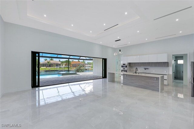 unfurnished living room with a tray ceiling and sink