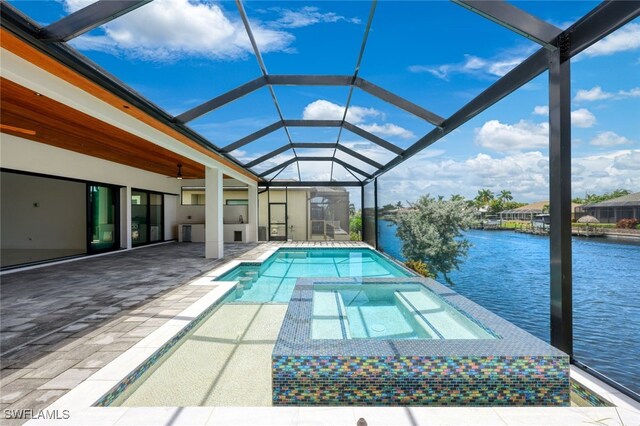 view of swimming pool featuring glass enclosure, a water view, a patio area, and an in ground hot tub