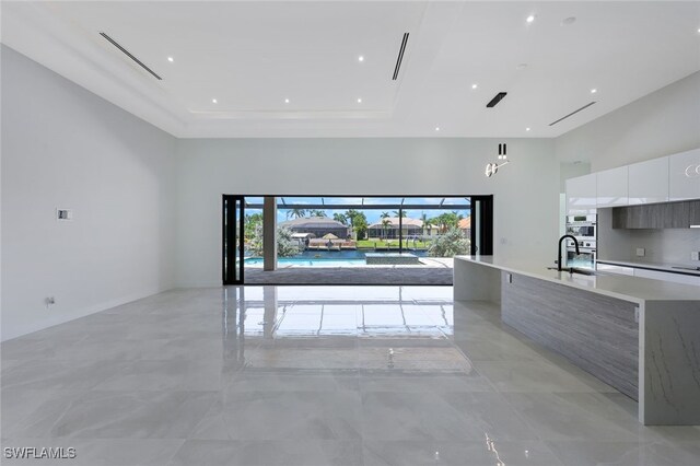 kitchen featuring white cabinets, double oven, plenty of natural light, and an island with sink